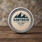 The Lodge Beard Balm in its cream-labeled silver tin on rustic wood against a stone backdrop